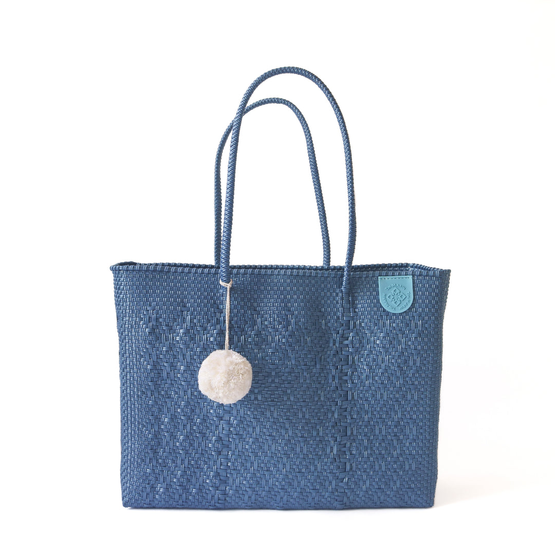 Tin Marin super tote in Maui Design, A blue oversized tote bag with a pompom decoration, and a shoulder strap.