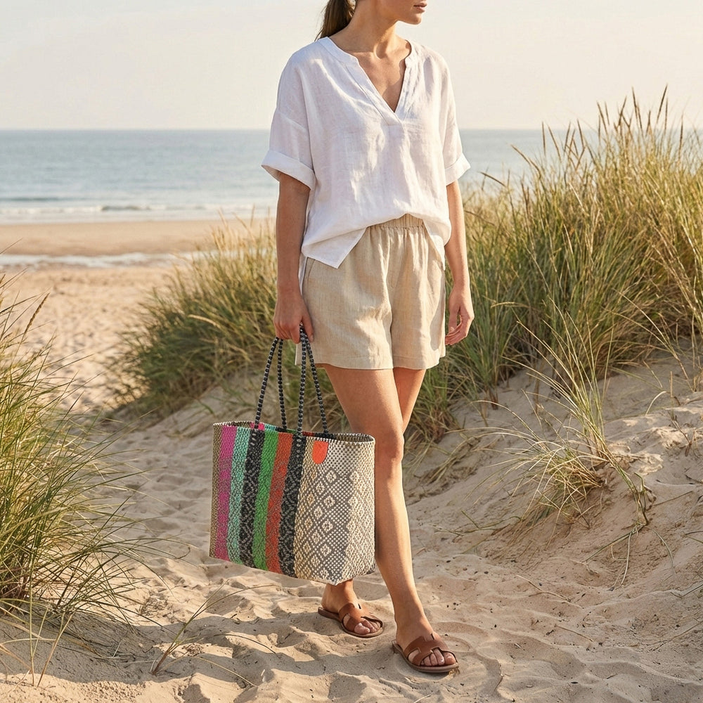 Model carrying Tin Marin Super Tote on coastal sand dune at sunset