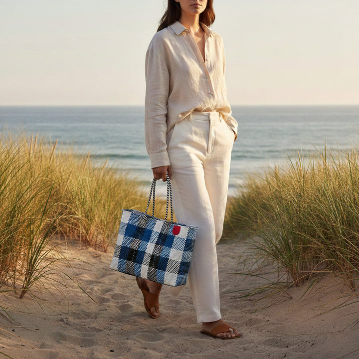 Model carrying Tin Marin Super Tote on coastal sand dune at sunset