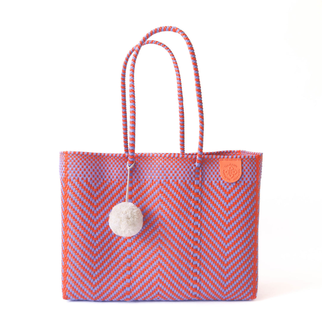 Tin Marin super tote in Positano Design, An orange and purple chevron oversized tote bag with a white pompom decoration,  and a shoulder strap.