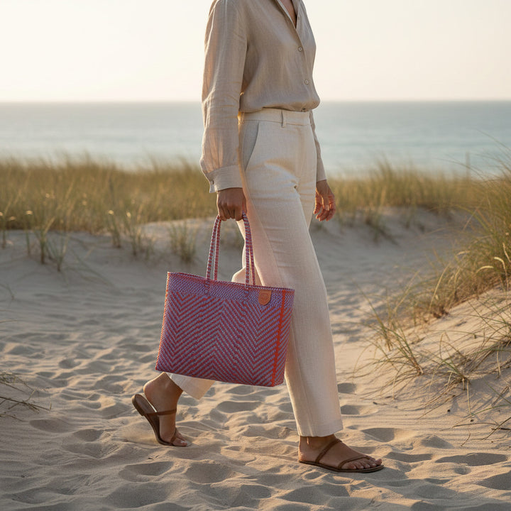 Model carrying Tin Marin Super Tote on coastal sand dune at sunset