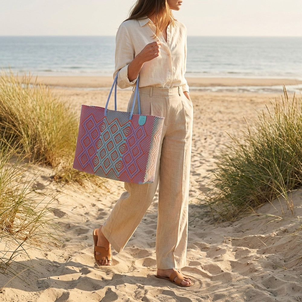 Model carrying Tin Marin Super Tote on coastal sand dune at sunset