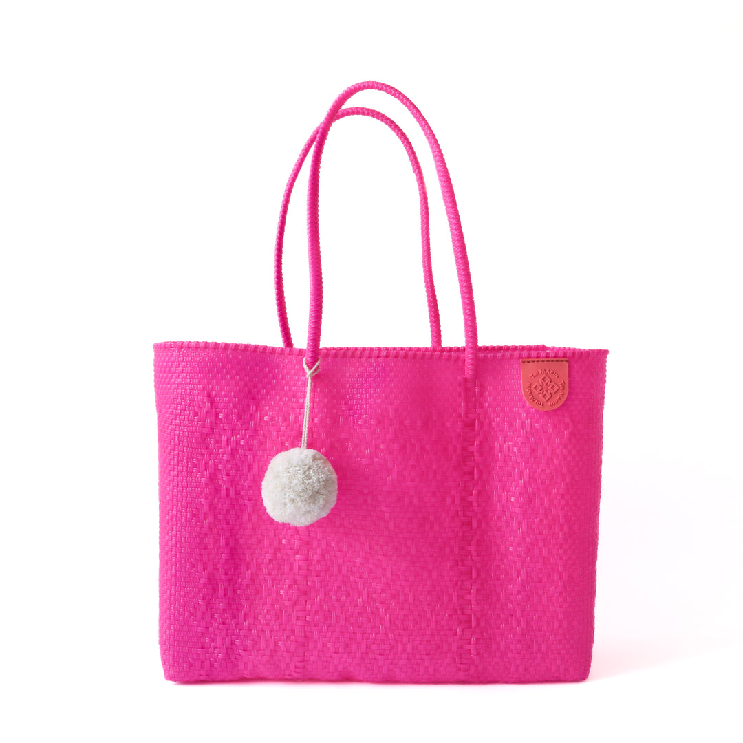 Tin Marin super tote in Vallarta Design, A hot pink oversized tote bag with a pompom decoration, and a shoulder strap.