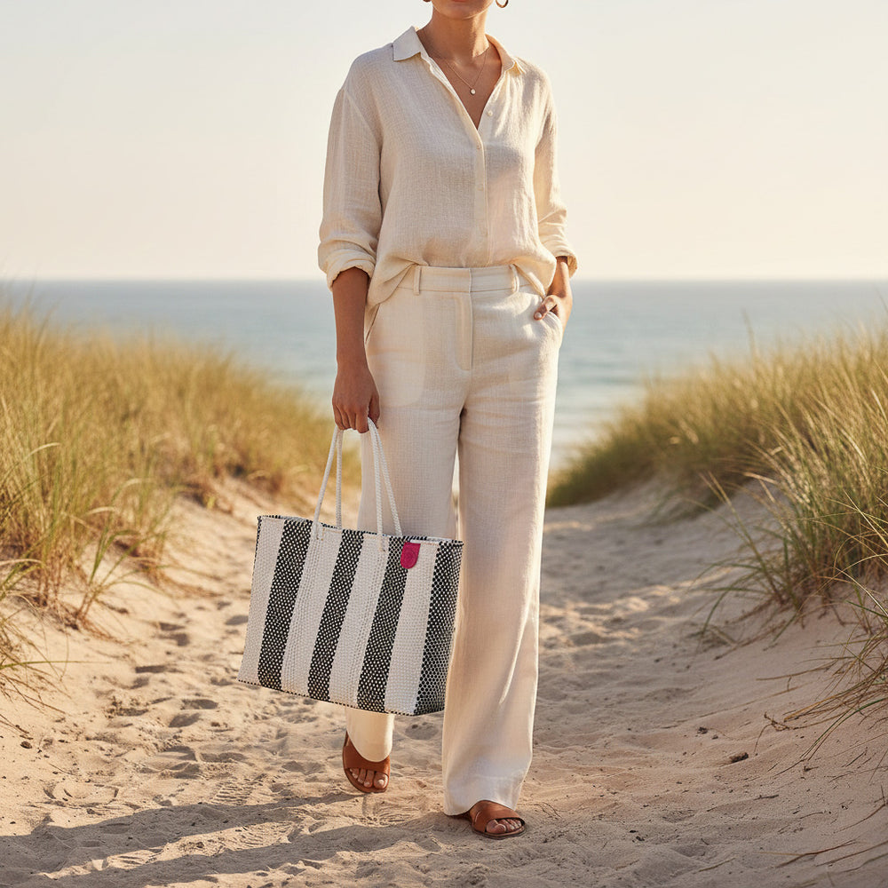 Model carrying Tin Marin Super Tote on coastal sand dune at sunset