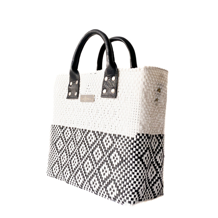 Side angle Tin Marin White Large woven crossbody bag in white and black with black leather — handmade from recycled plastic in Mexico by Tin Marin