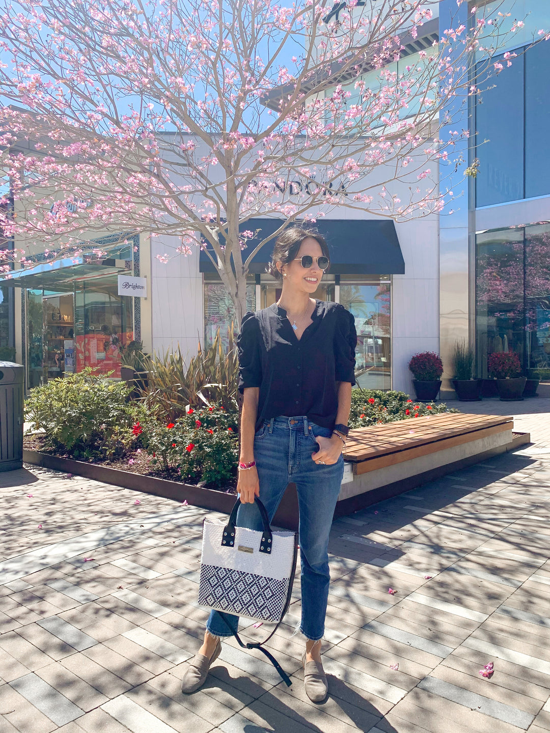 Woman wearing Tin Marin White Large woven crossbody bag in white and black with black leather — handmade from recycled plastic in Mexico by Tin Marin