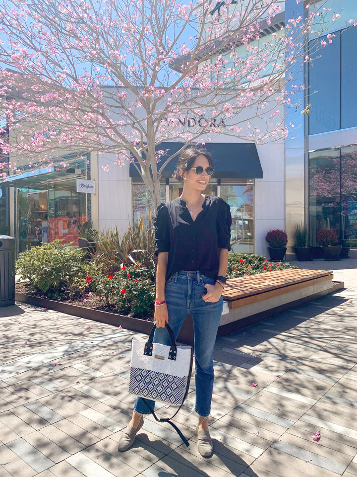 Woman wearing Tin Marin White Large woven crossbody bag in white and black with black leather — handmade from recycled plastic in Mexico by Tin Marin